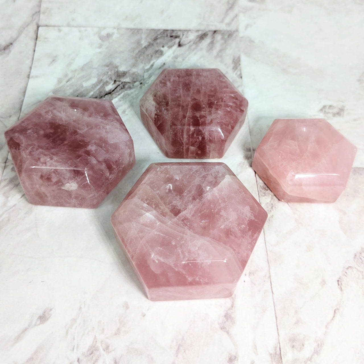 Three rose quartz hexagon-shaped sphere holders on marble table. #LV2319