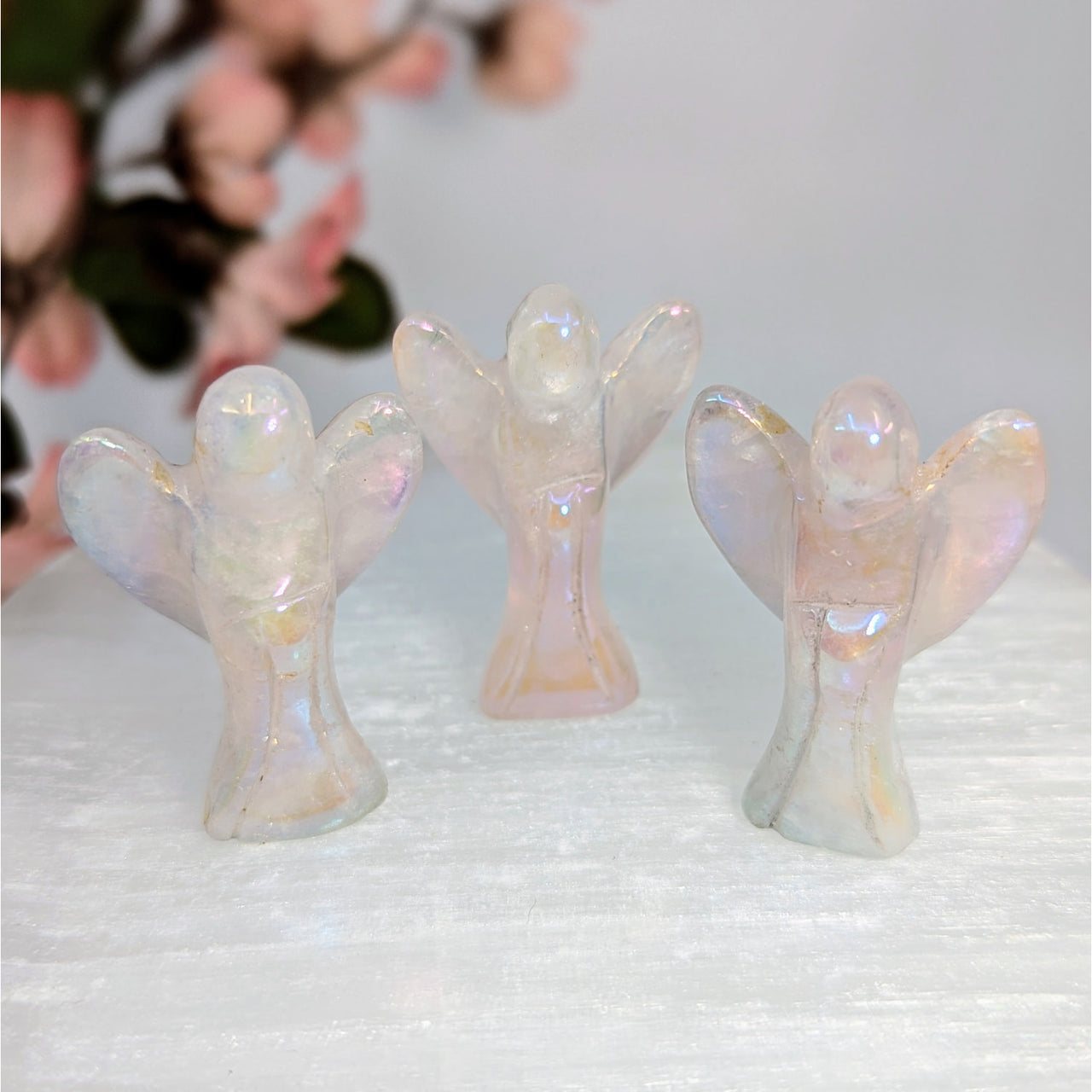 Three iridescent angel figurines displayed in the Rose Quartz Aura 1.5 inch Mini Angel Carving