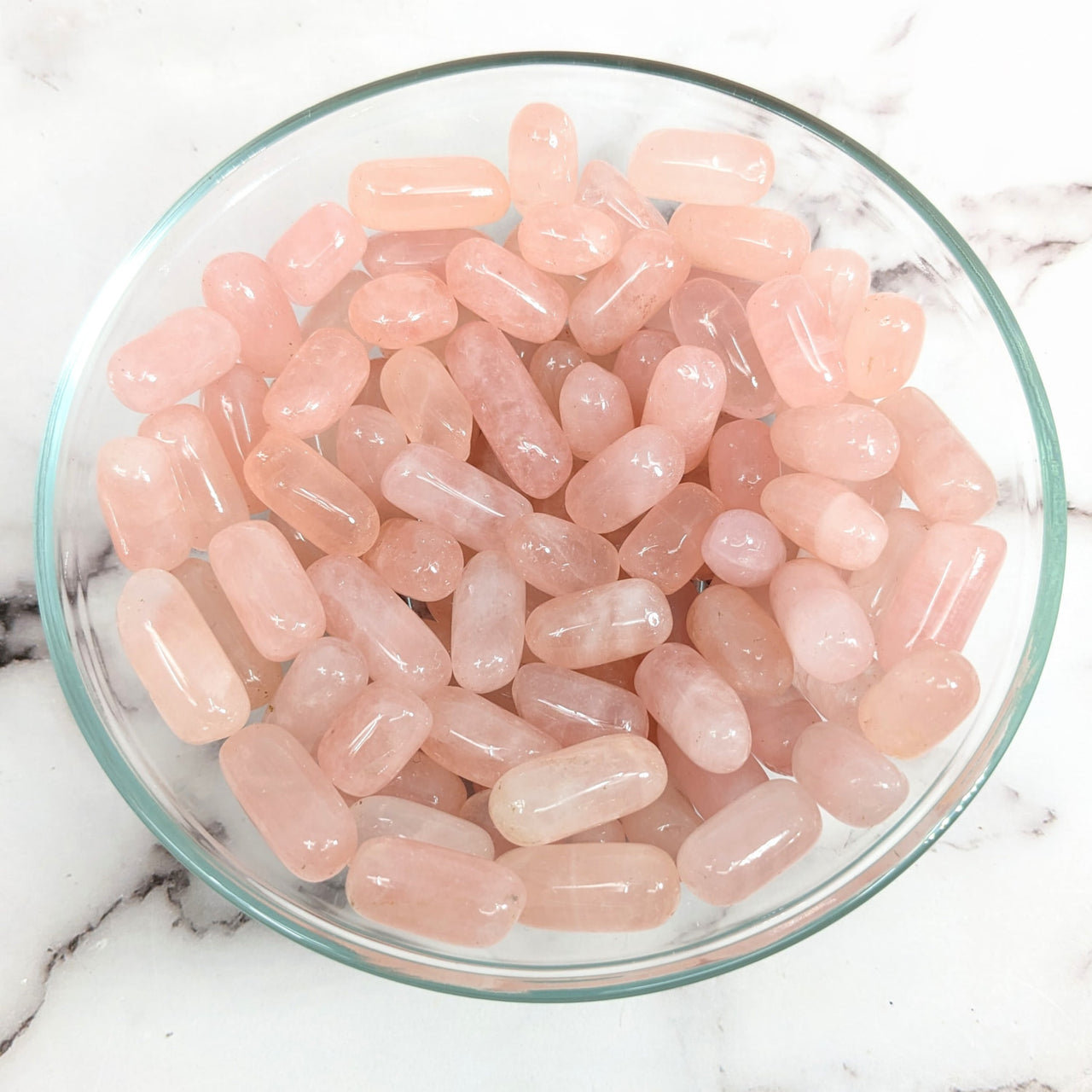 Arafed bowl of rose quartz tumbled stones on a marble counter; Item #LV1535