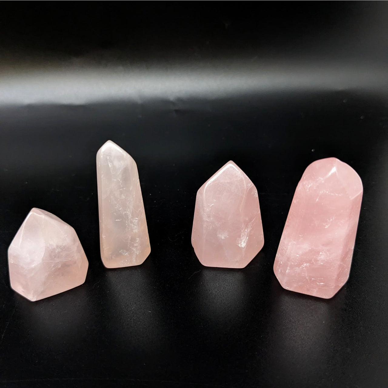 Rose quartz tower collection featuring three pink quartz points on a sleek black surface