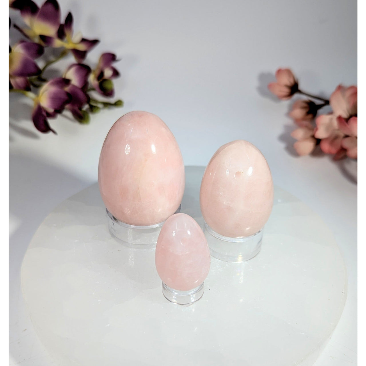 Three smooth translucent pink rose quartz yoni eggs on acrylic stands, 1-2 inches