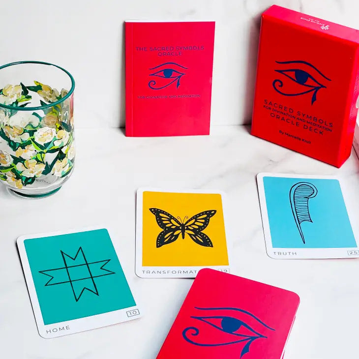 Sacred Symbols Oracle Deck by Marcella Kroll with cards on display next to a glass of water