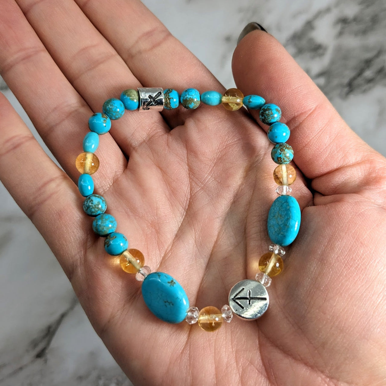 Hand holding Sagittarius Zodiac Handmade Beaded Bracelet with turquoise and gold beads