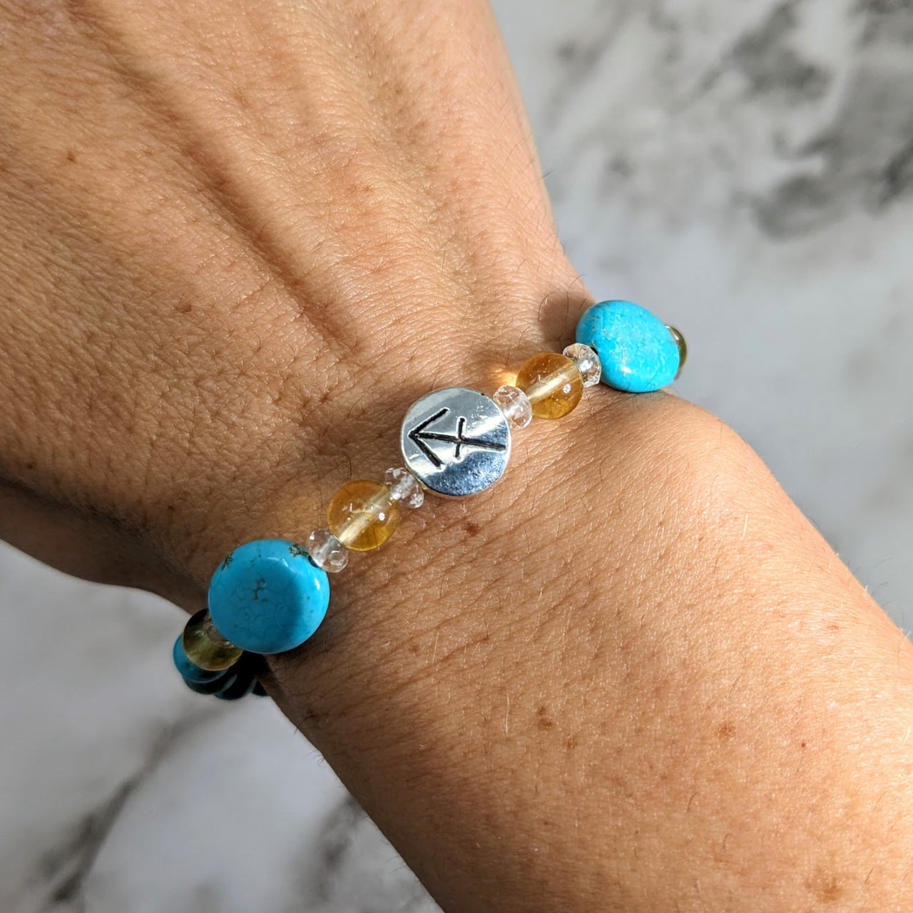 A woman’s hand with Sagittarius Zodiac Handmade Beaded Bracelet in turquoise and yellow beads