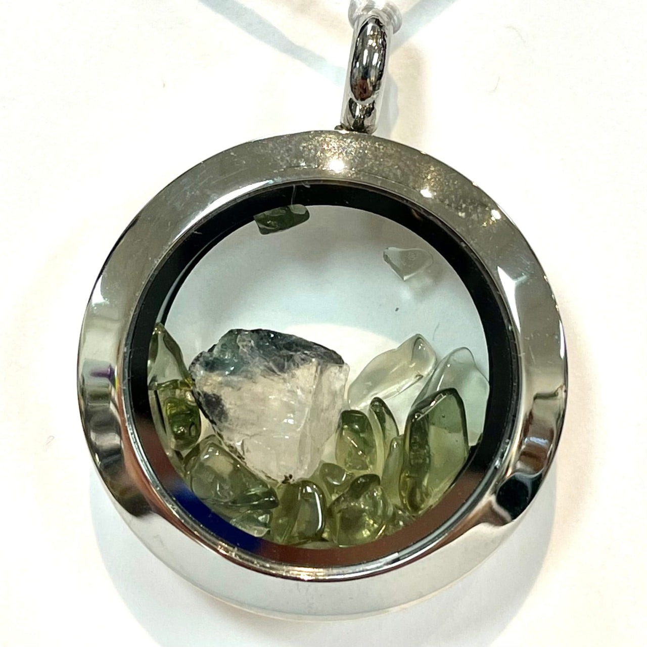 Round silver Phenacite locket pendant with crystals and stones behind glass