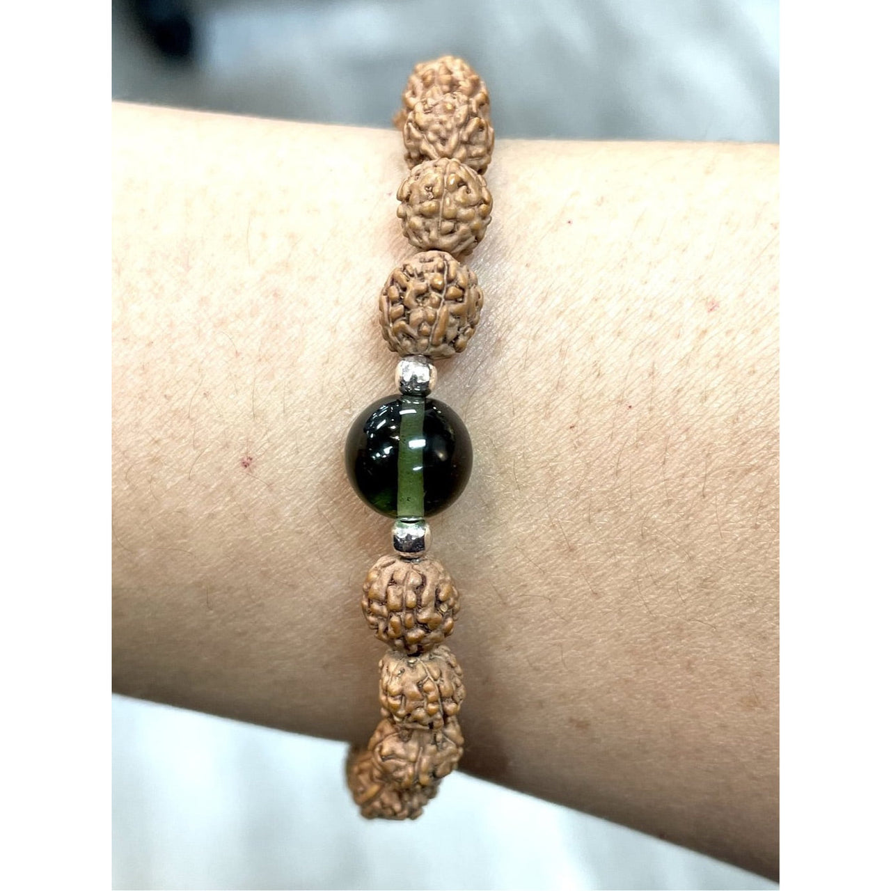 Beaded bracelet featuring Rudraksha beads and a dark green Moldavite centerpiece, perfect for referral history