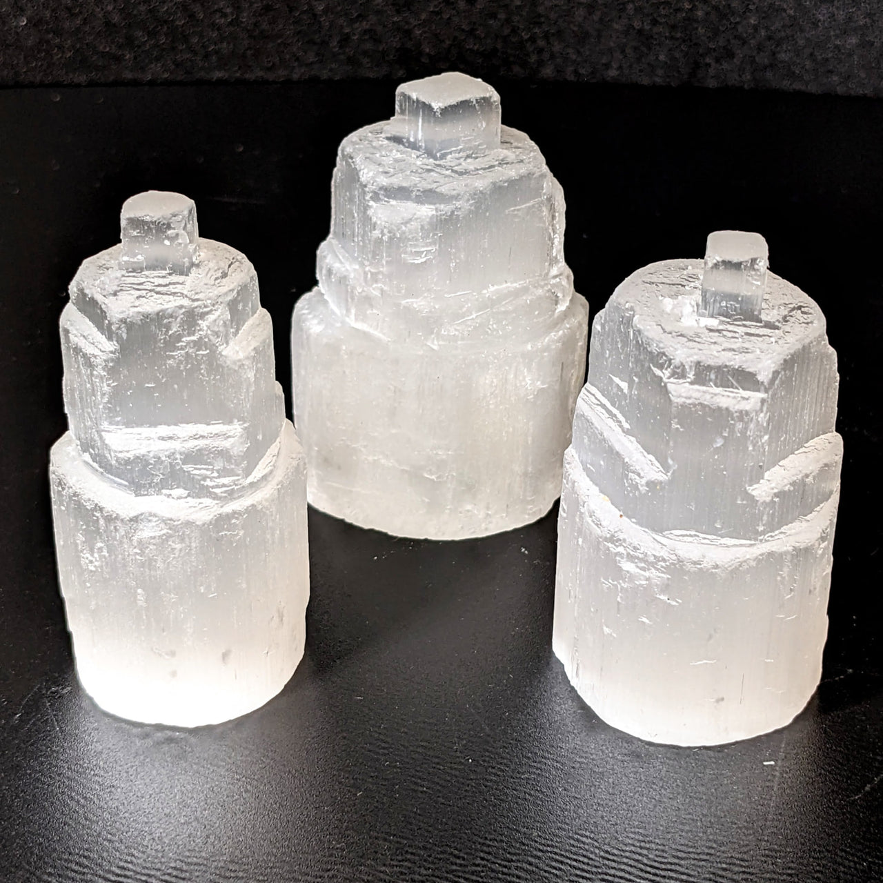 Selenite 2.25’ Mini Tower (115g) #SK9255 with three ice pieces on a sleek black surface