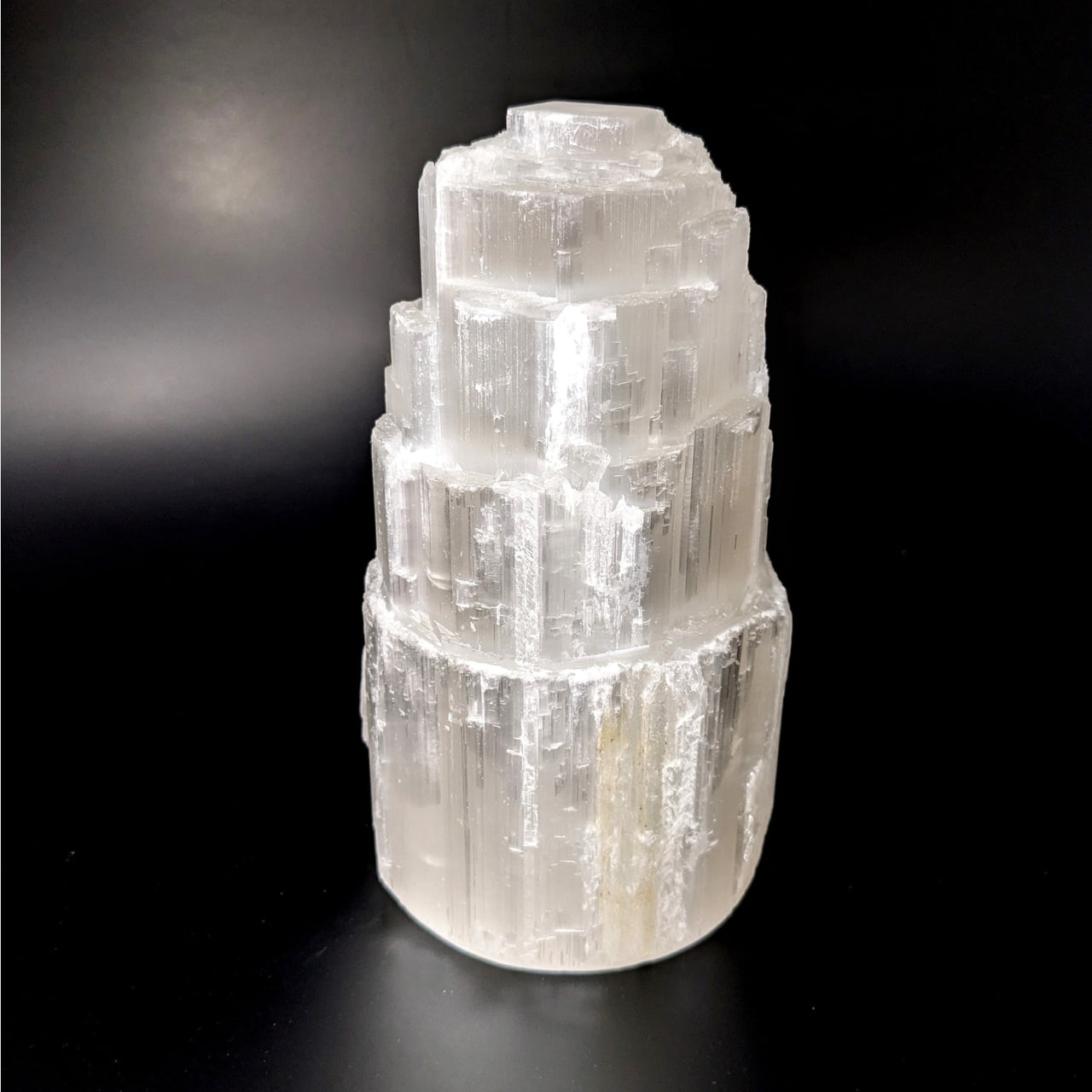 Close-up of Selenite 5.7’ Rough Tower Lamp on a black surface with bulb and cord, product #LV4140