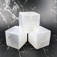 Thumbnail for Three white selenite cubes on a marble surface - Selenite Cube Carving #Q170