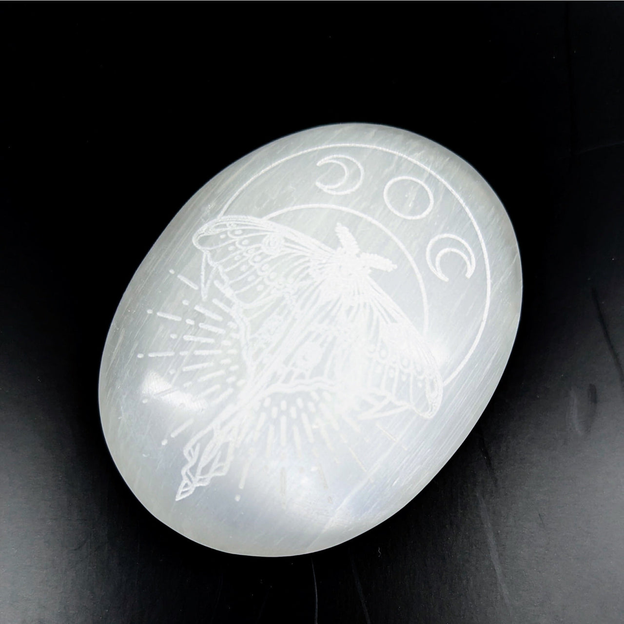 Luminous white Selenite palm stone engraved with moth and moon phases, 3-inch size