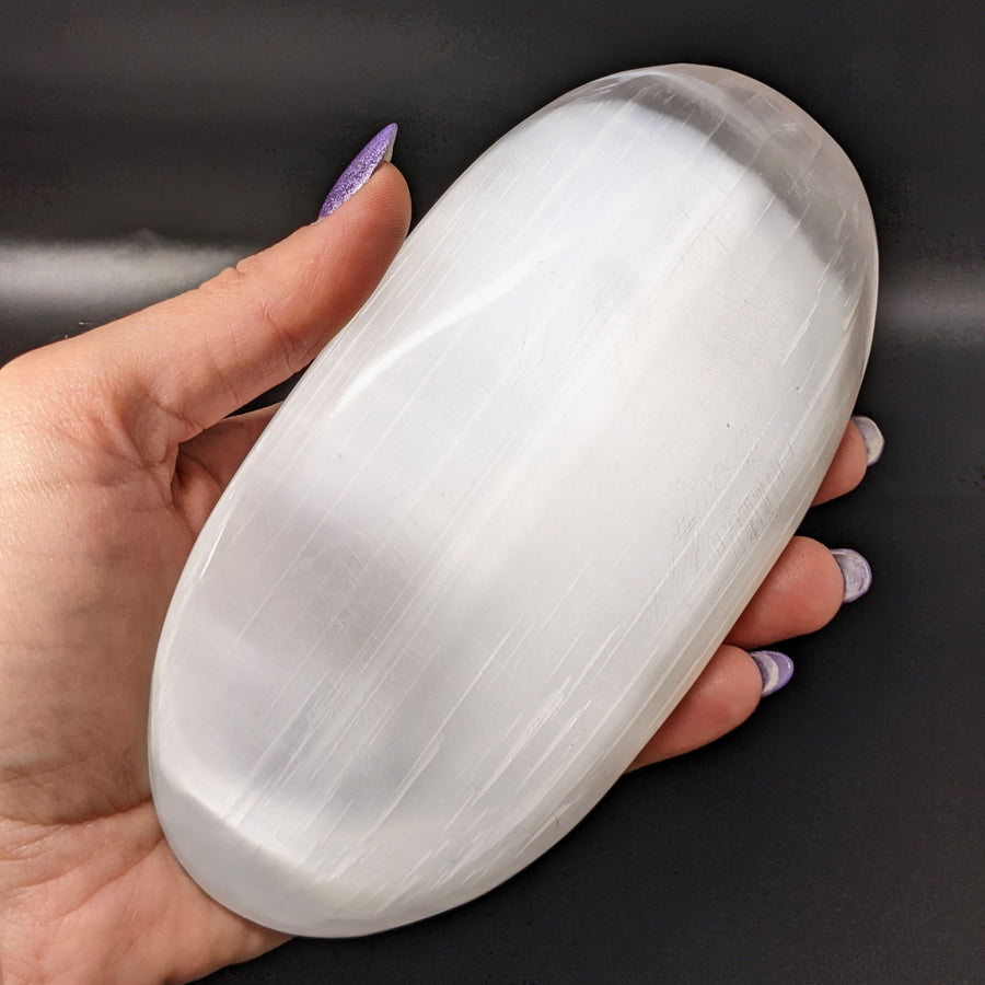 A woman holding a large Selenite Jumbo Palm Stone, perfect for healing and meditation