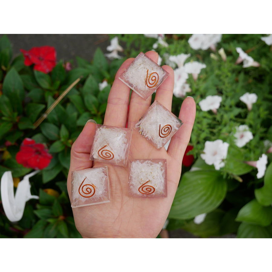 Clear square-shaped quartz crystal healing pendants with copper spiral and white crystalline fill in selenite orgonite pyramid