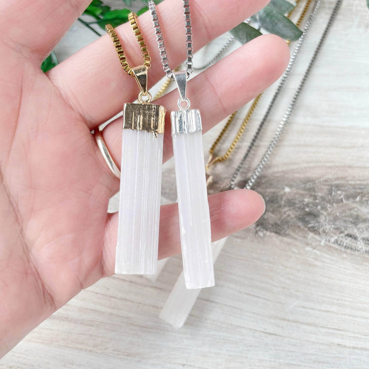 Hand holding gold and silver selenite raw bar pendant necklaces LV9192
