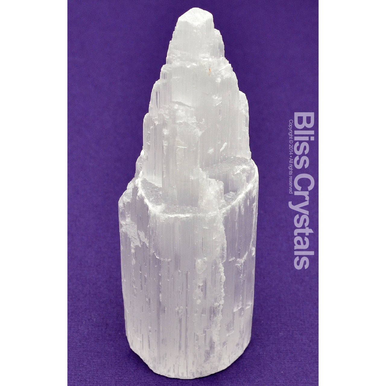 Close-up of SELENITE Skyscraper Tower 4’ Rough White Stone Crystal against a purple background