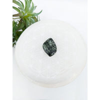 Thumbnail for Dark green Seraphinite 2” cabochon resting on a white surface, showcasing its natural beauty