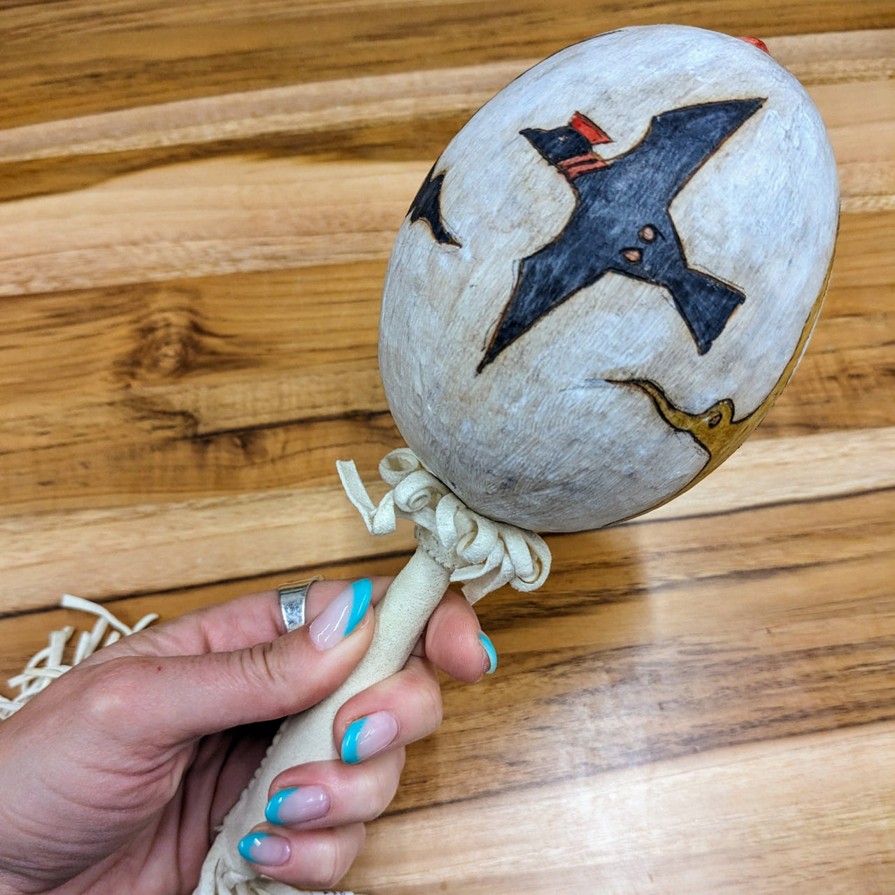 Hand holding Shoshone Gourd Rattle wooden ball, made by Pete Yellowjohn