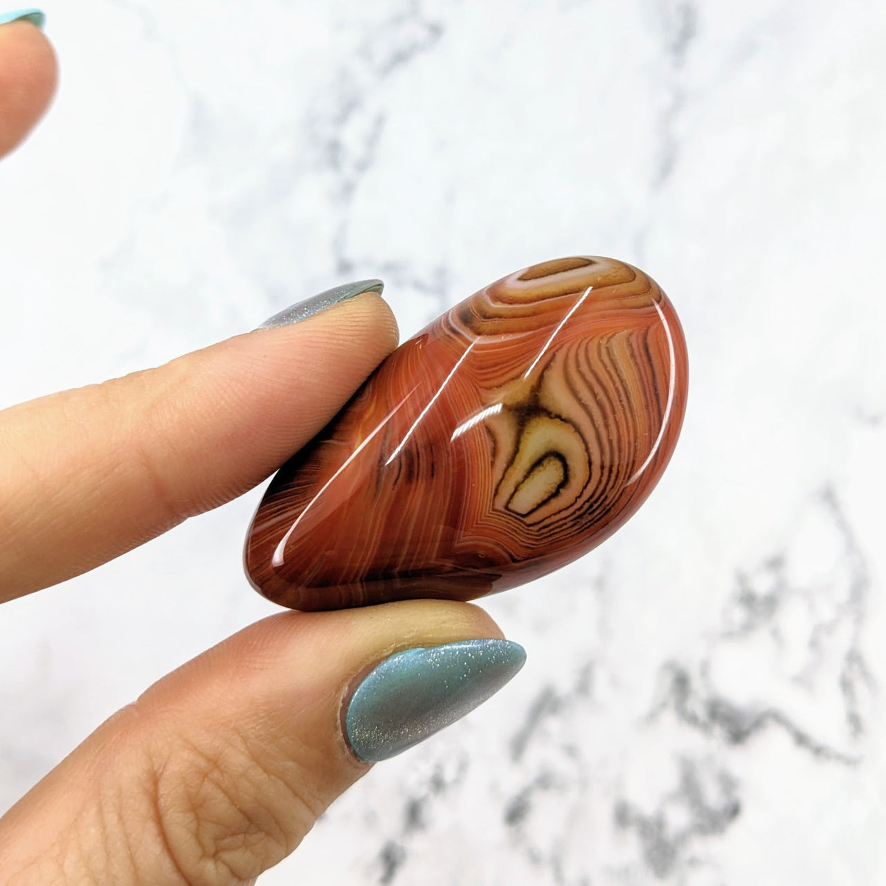 Hand holding Silk Agate Pebble Stone, red and brown marble, 1.6 - 2.2 inches #LV1573