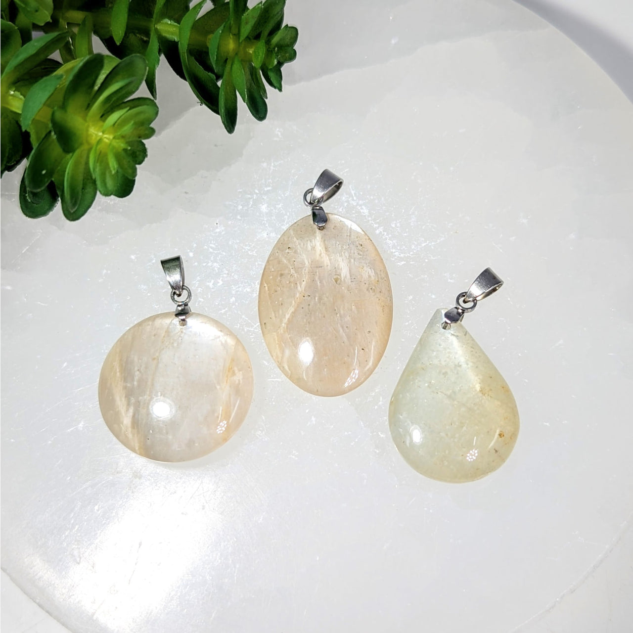 Three pale yellowish moonstone crystal pendants with silver clasps