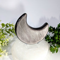 A polished silver crescent moon-shaped silversheen obsidian stone with a glossy metallic finish 3.5 inches