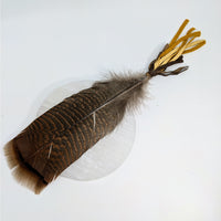 Brown striped feather with yellow ribbons on a smudge fan for sage and Palo Santo