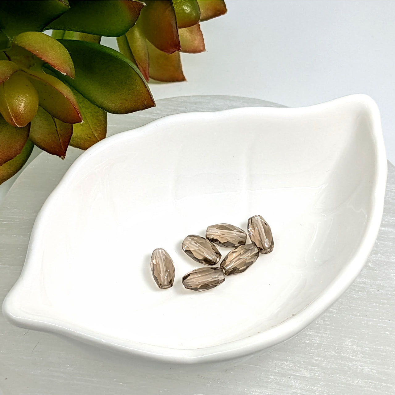 Sunflower seeds in a white dish with Smoky Quartz 10mm Faceted Cylinder Beads