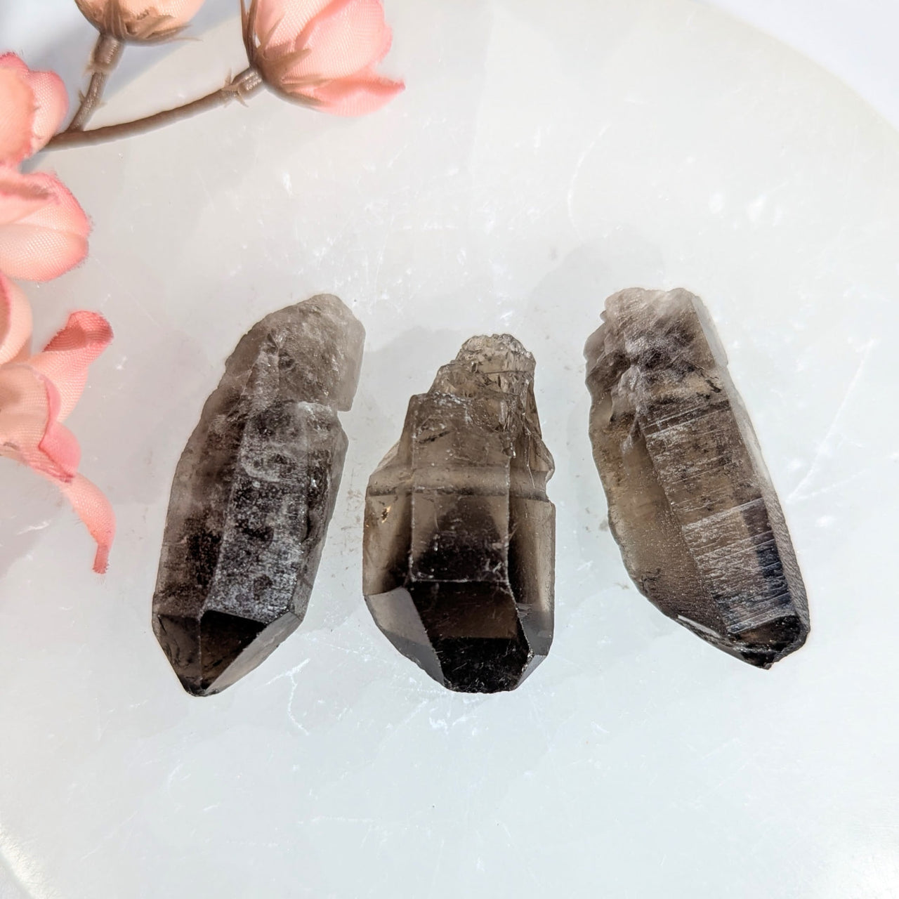 Three dark smoky quartz crystals with faceted pointed tips and natural inclusions for jewelry and gemstone use