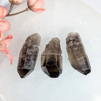 Three dark smoky quartz crystals with faceted pointed tips and natural inclusions for jewelry and gemstone use