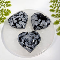 Three polished black silver snowflake obsidian 2in hearts on quartz plate BC0866