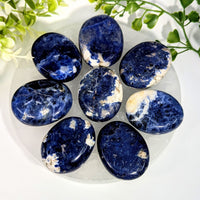 Seven polished sodalite palm stones 1.6 to 1.8 inches with deep blue base and white to light gray veining