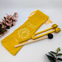 Golden tuning fork with mallet and yellow pouch for Solar Chakra healing therapy