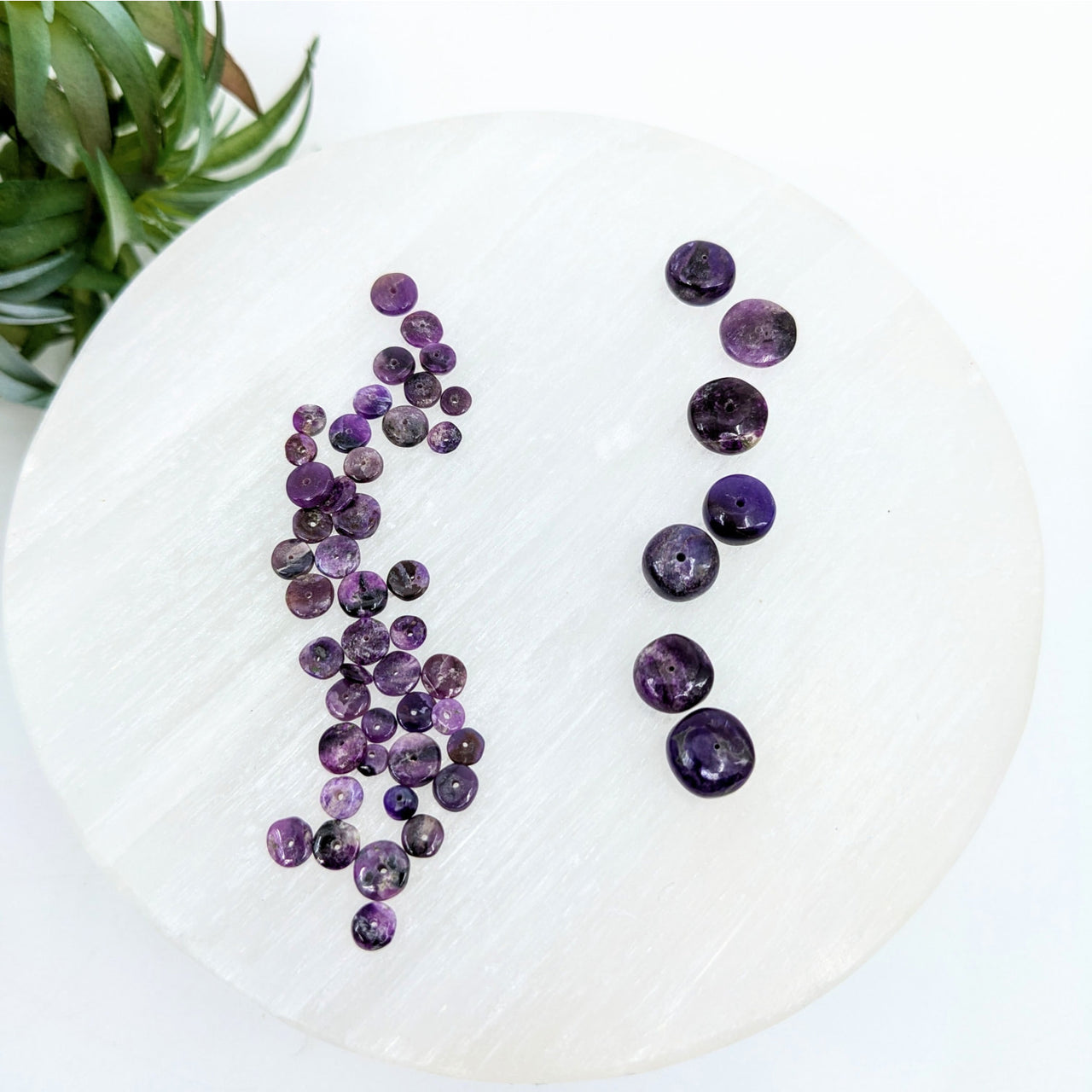 Purple Sugilite Rondelle Beads arranged vertically on a white surface