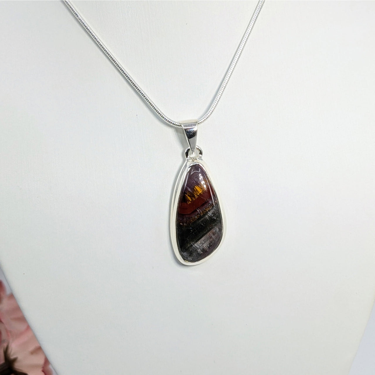 Teardrop-shaped amber and black stone pendant on silver chain in Super 7 jewelry collection