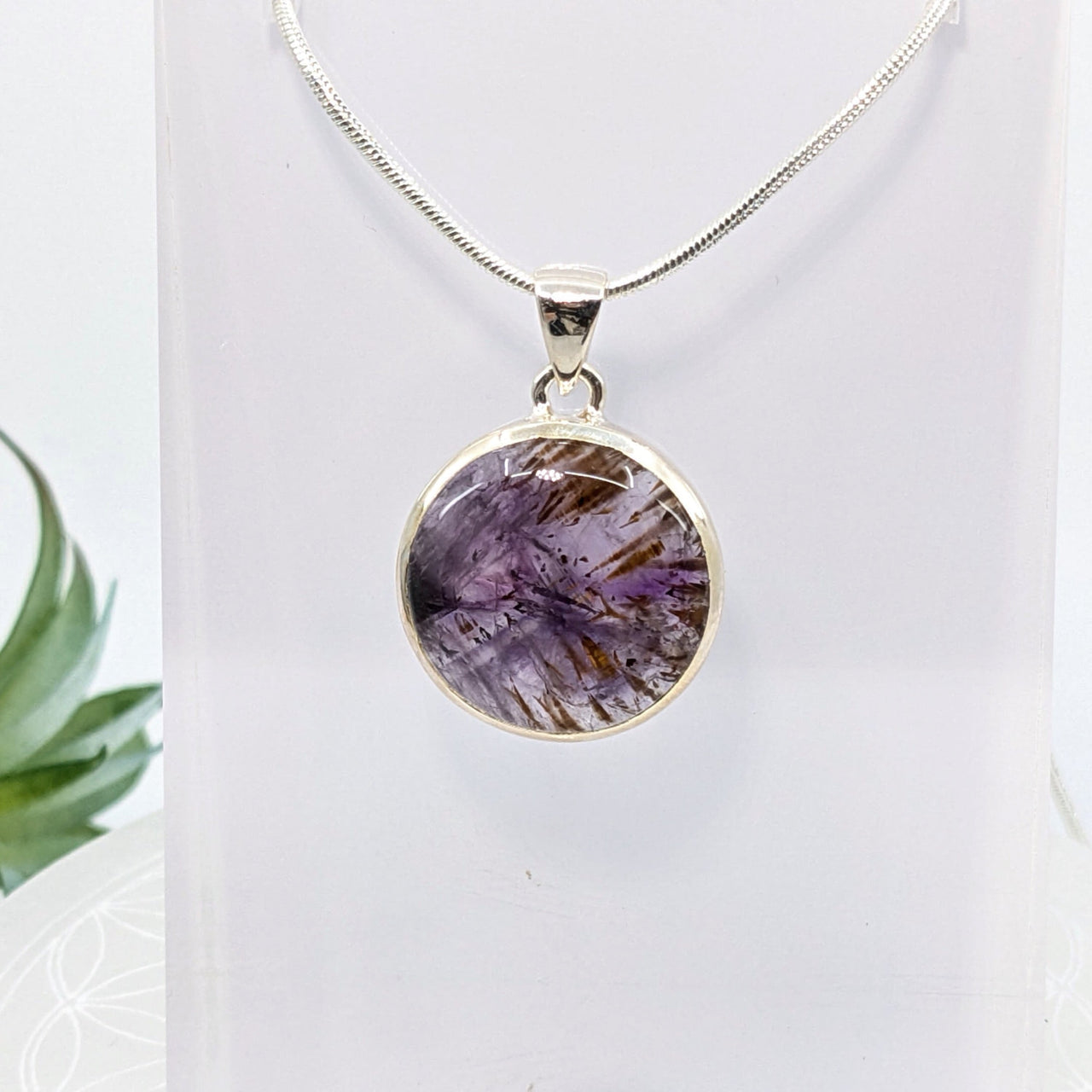 Round pendant with purple crystal and natural inclusions on a chain necklace