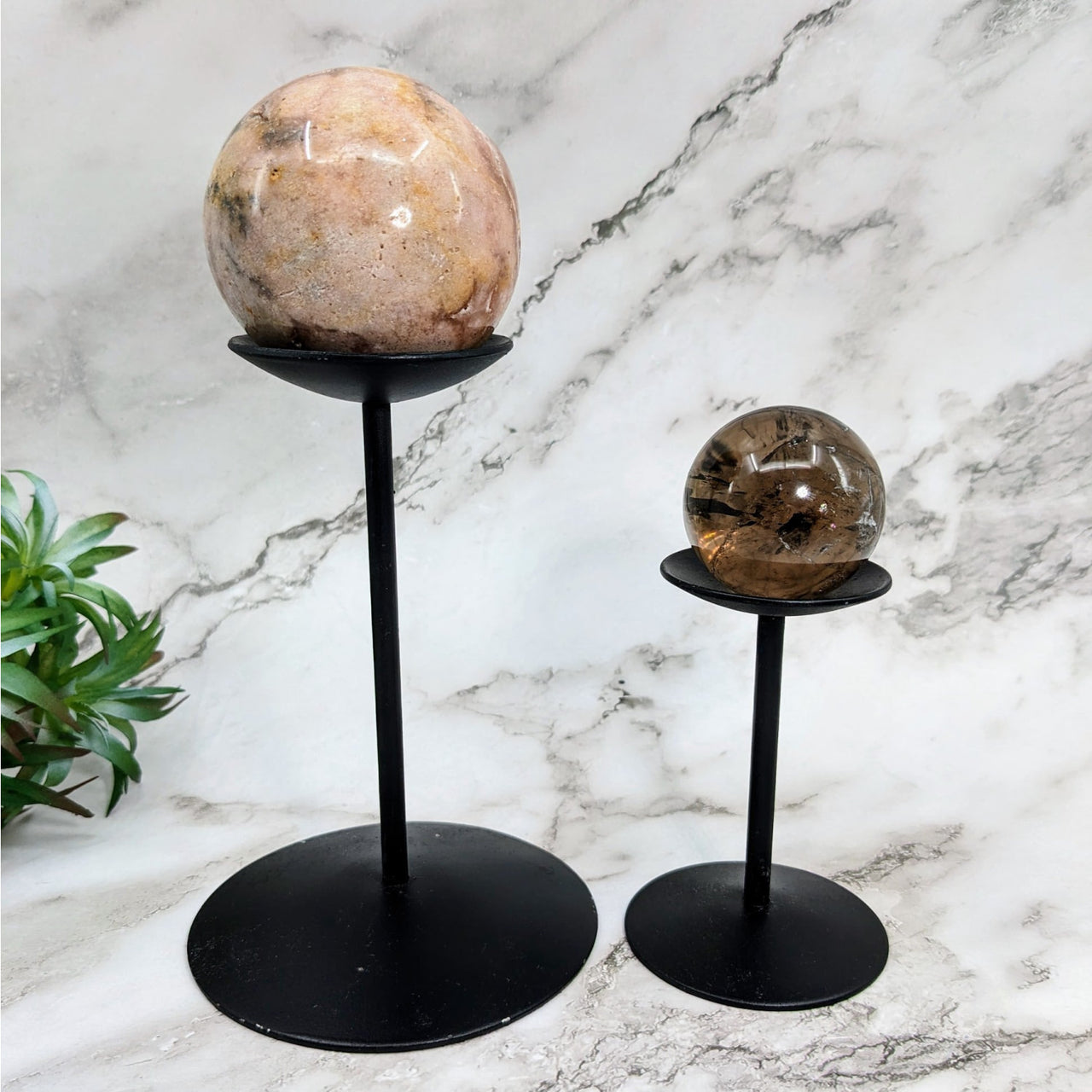 Tall black metal stands holding large rocks, featured in the Tall Metal Sphere Stand #LV4034