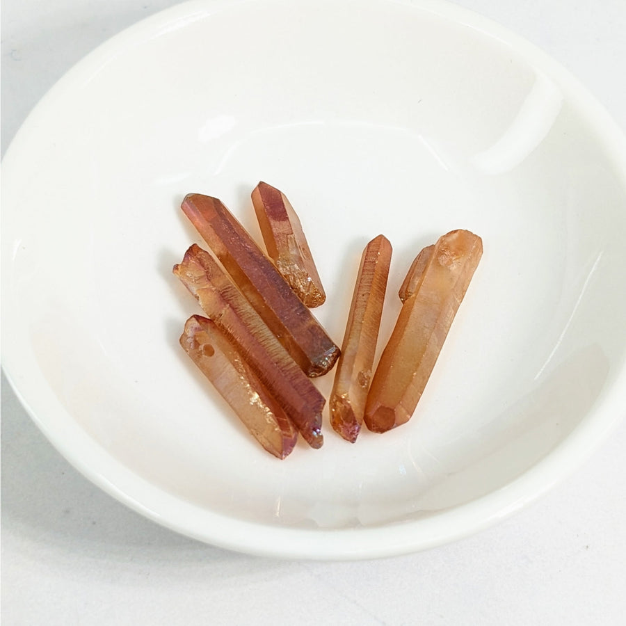 Tangerine Aura Quartz Point Top Drilled Bead 12 Pack displayed with bacon on a white plate