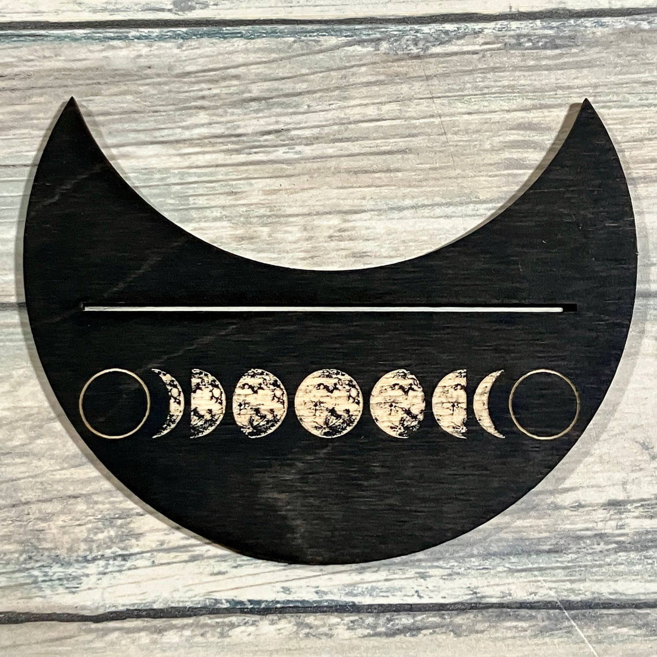 Black crescent moon phase wall art with gold rings and white phases