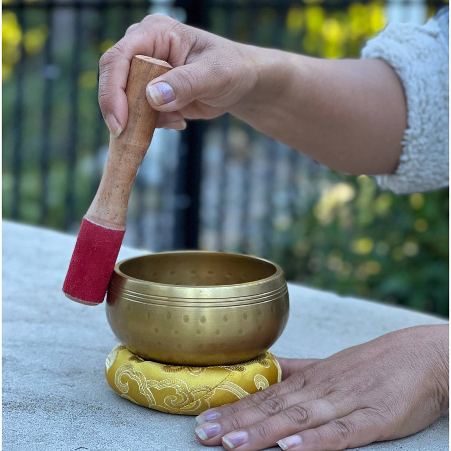Tibetan Brass Gong Meditation Singing Bowl with Mallet on a wooden surface