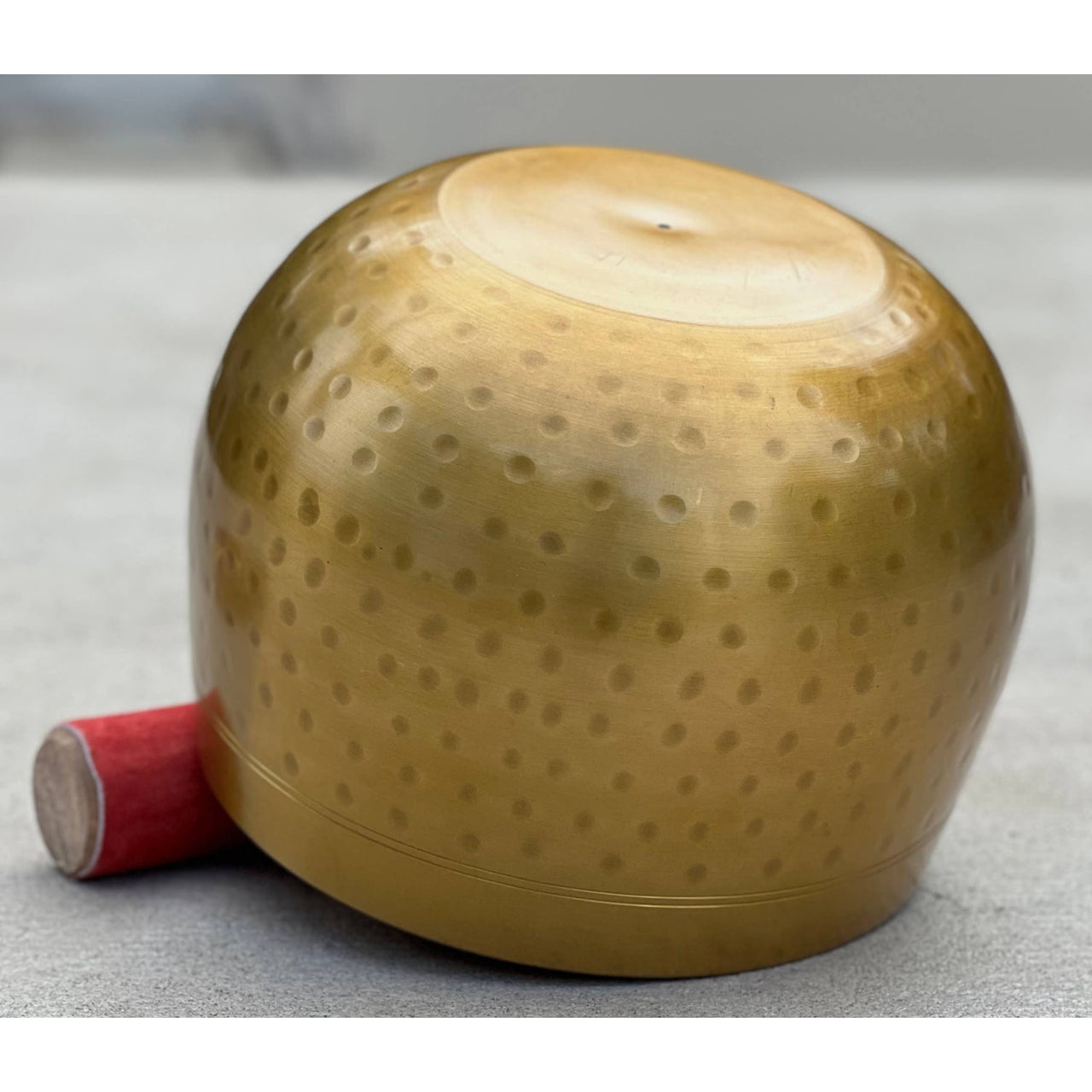 Gold-colored spherical firework with red fuse next to Tibetan Brass Gong Meditation Singing Bowl