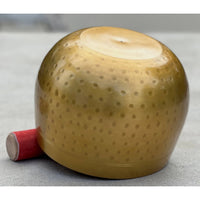 Gold-colored spherical firework with red fuse next to Tibetan Brass Gong Meditation Singing Bowl