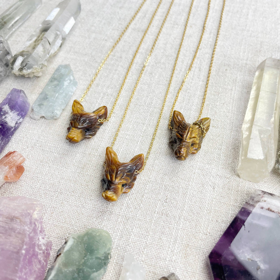 Three golden tiger head necklaces with intricate carvings on delicate chains
