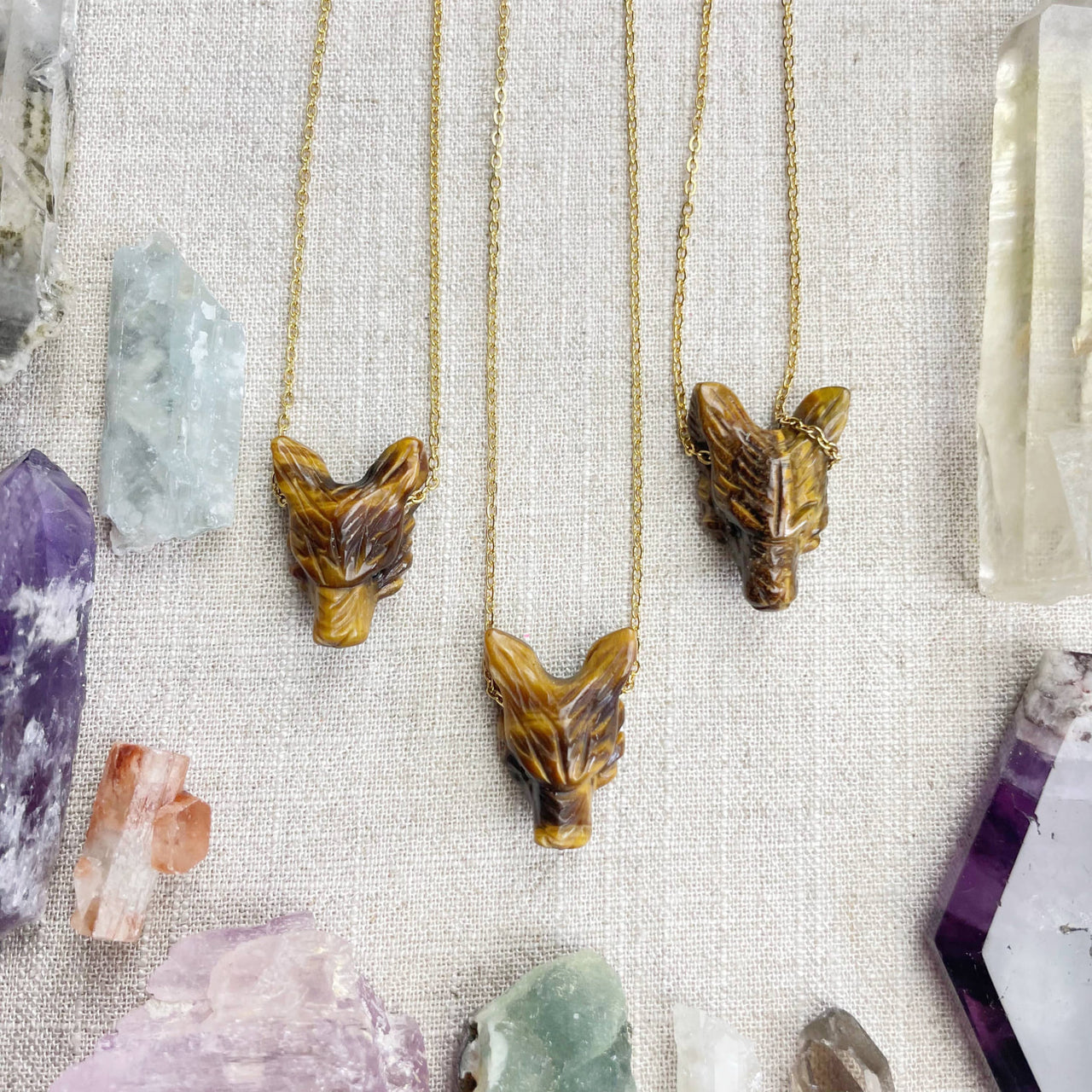 Three intricately carved tiger’s eye fox head necklaces with polished amber-brown surfaces