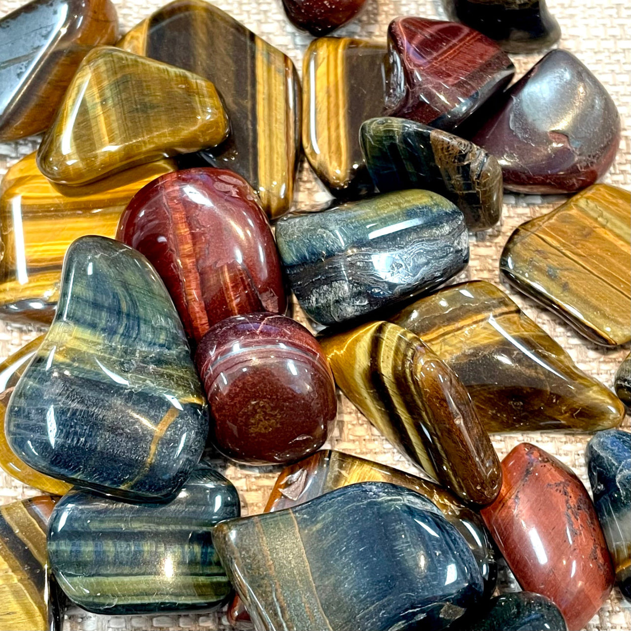 Polished gemstones and minerals in yellow, red, and blue featuring Tiger’s Eye Tumbled