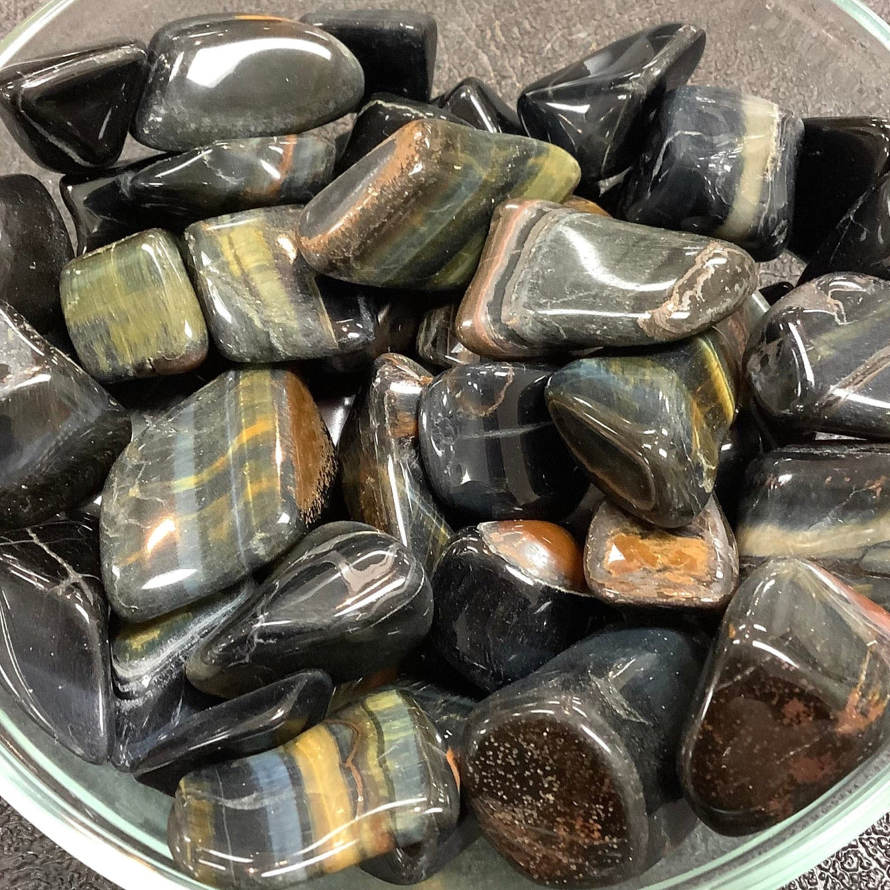 Polished black obsidian stones with colorful bands in Tiger’s Eye Tumbled #T323