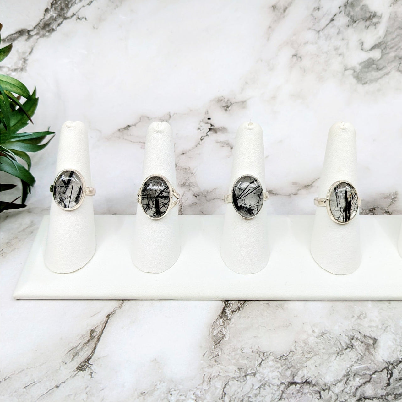 Three white candles on a marble counter next to Tourmalinated Quartz .6’ Oval S.S. Ring #LV4612