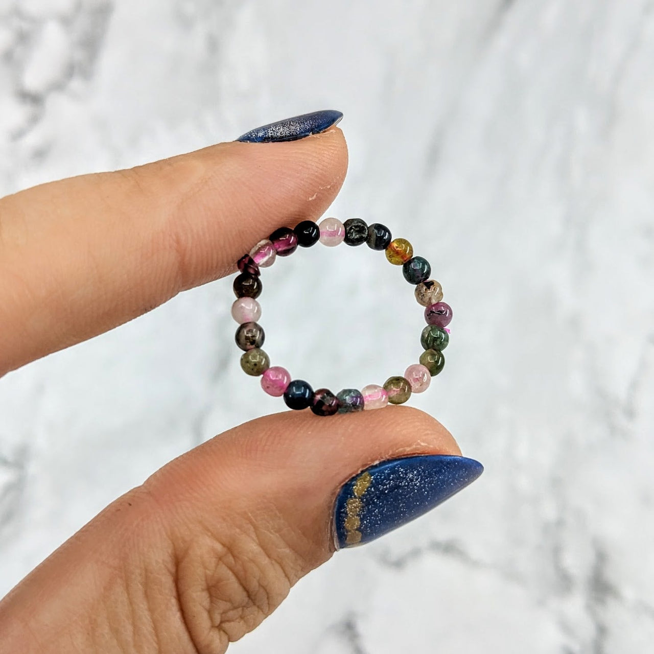 Woman’s hand holding Tourmaline Mixed 1’ Beaded Stretchy Ring #LV1970 with colorful beads