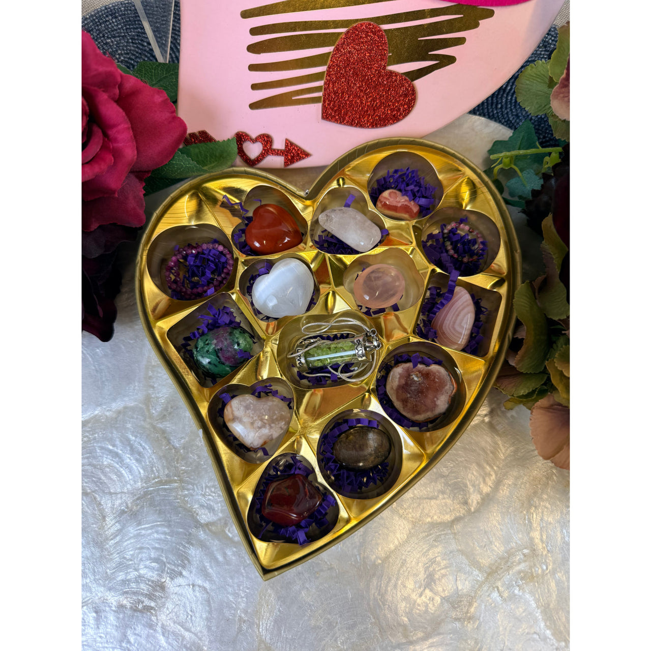 Valentines crystal candy box with gold heart filled with polished gemstones in purple paper