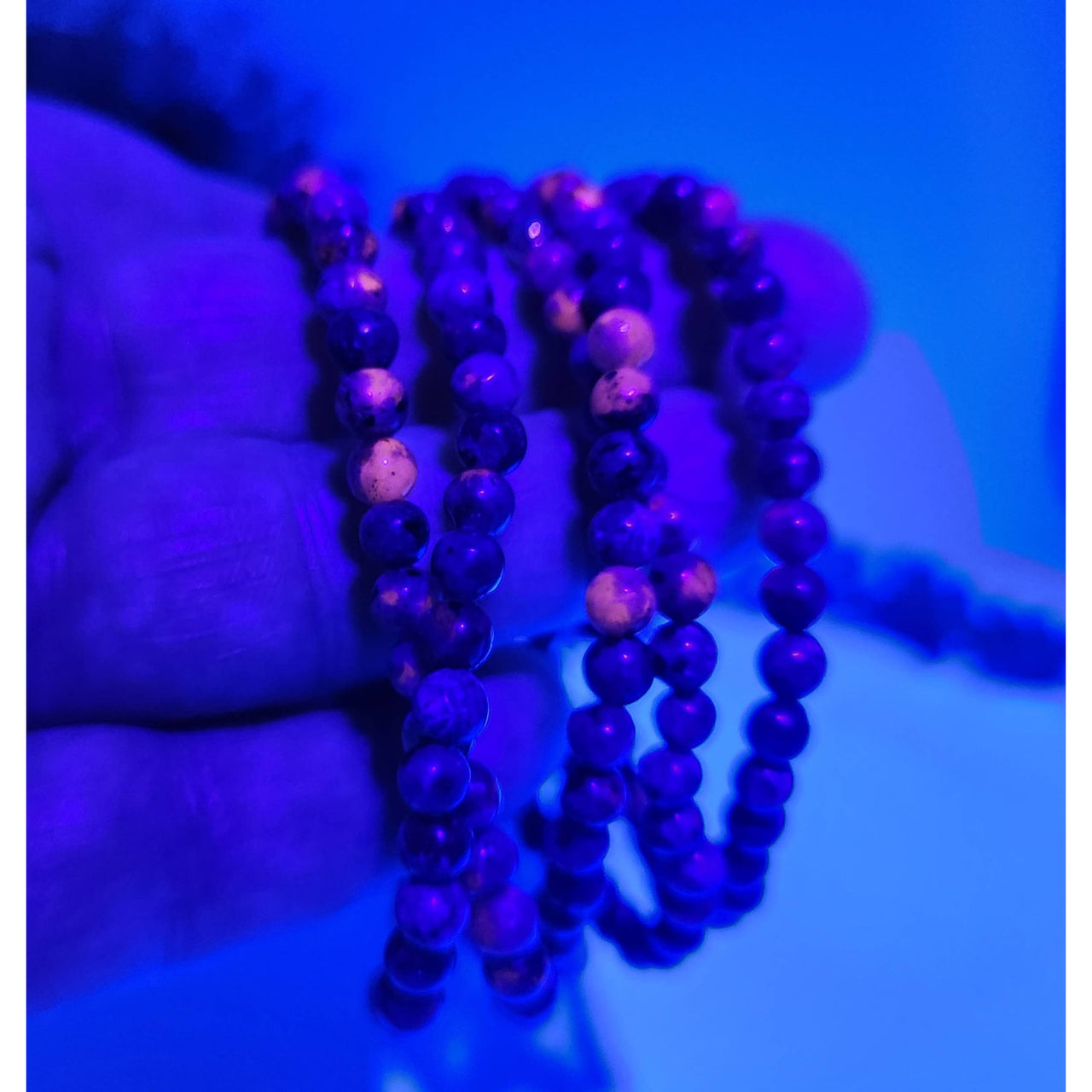 Yooperlite stretchable gemstone bracelet with dark purple beads, pink accents, UV reactive