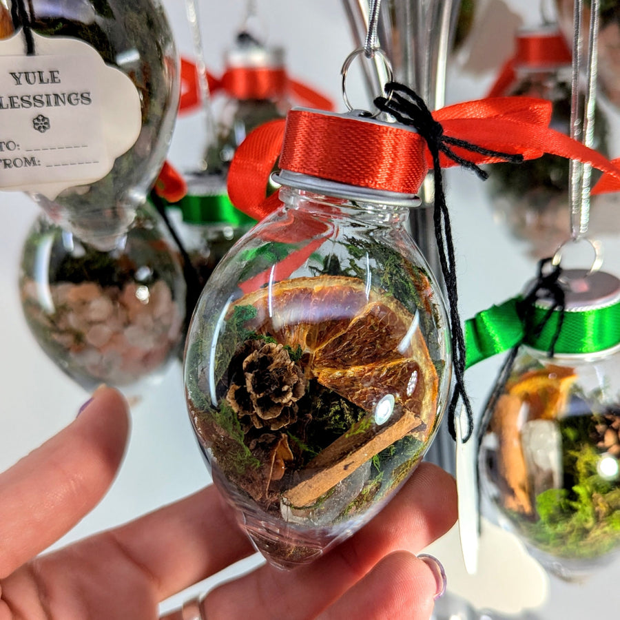 Yule Blessings 3.5’’ crystal ornament with dried orange slices, moss, pinecones, cinnamon sticks, red ribbon, black string, and quartz point