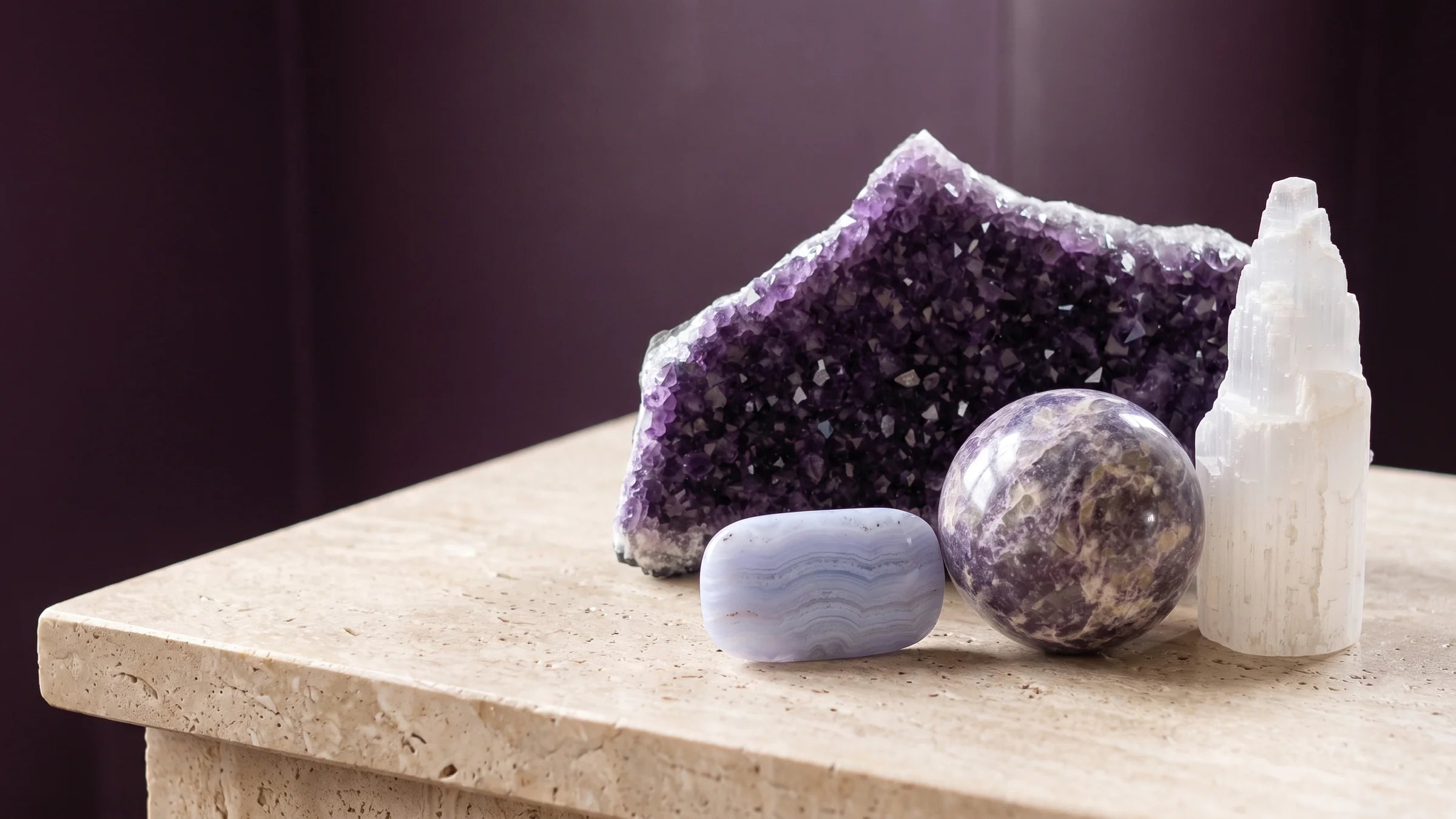 Amethyst, lepidolite, blue lace agate and selenite resting in soft light.