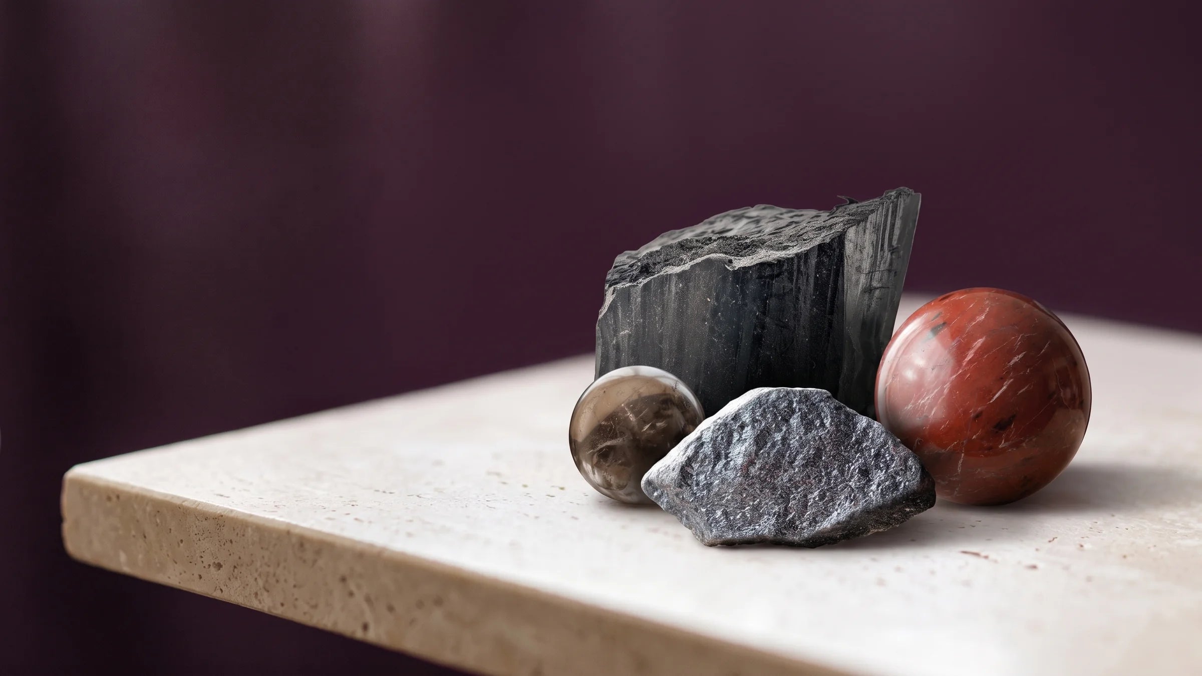 Black tourmaline, hematite, smoky quartz and red jasper on a warm neutral surface.